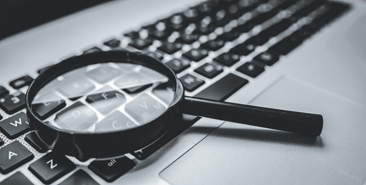 Forstørrelsesglass som ligger på tastaturet på en bærbar datamaskin