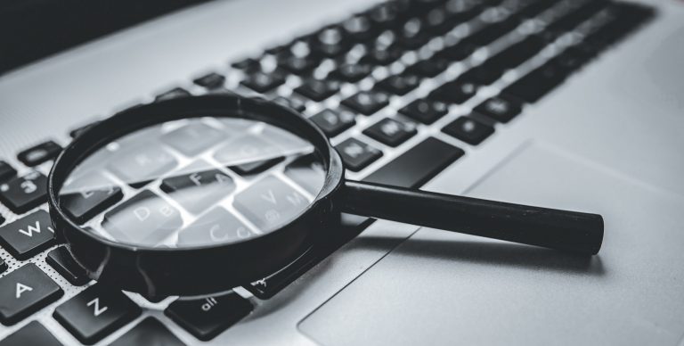 Forstørrelsesglass som ligger på tastaturet på en bærbar datamaskin