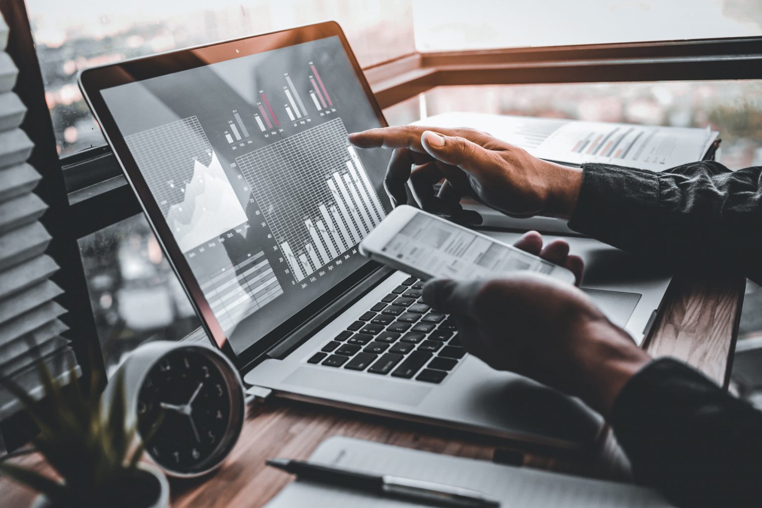 Hender som peker på en bærbar datamaskin med grafer på