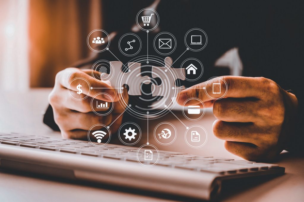 Mann som holder to puslespillbrikker over et tastatur med illustrasjon av elementer fra en nettside over