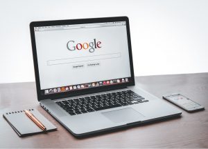 Bærbar datamaskin og mobiltelefon som viser nettleser med Google