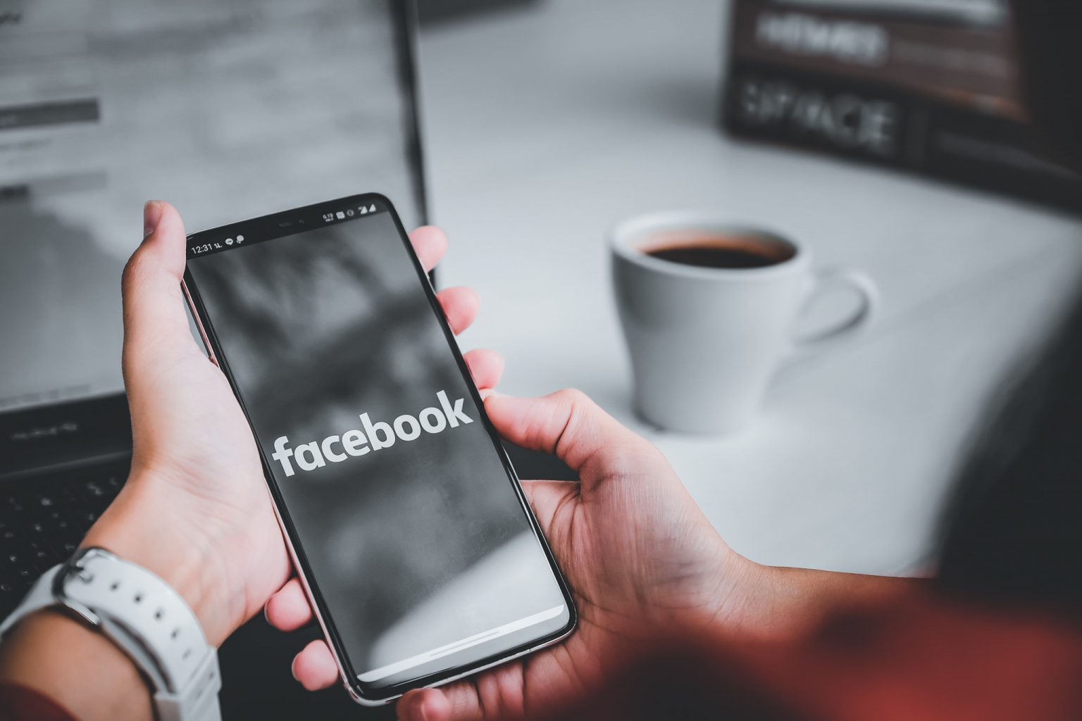 Hender som holder en mobil med facebook